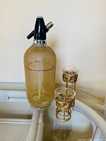 Soda siphon with gold-tone mesh and two matching wire candle holders with glass inserts