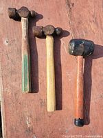 Three hammers laid on wooden surface