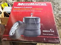 Front of boxed MotoMaster tire stand showing product image and warranty info