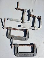 Overview of all four clamps on surface: two F-style bar clamps and two C-clamps
