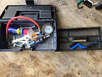 Toolbox opened displaying contents: wrenches, gauge, tube, brushes, hardware