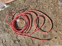 Coiled red air hose on ground