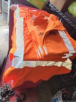 Stack of folded orange reflective shirts showing quantity and reflective tape