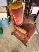 Front view of rocking chair showing wood frame, red and gold velvet upholstery