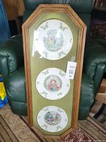 Front view showing three plates in green-matted oak frame