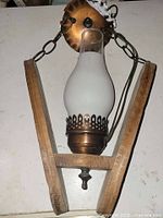 Front view of light showing copper canopy, chains, wood frame and glass chimney shade