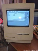 Front view of Macintosh Classic II powered on showing system desktop