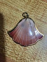 Front of shell pendant showing pink gradient and gold edging