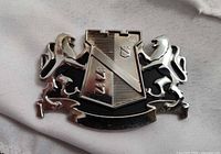 Front view of chrome crest badge showing heraldic design