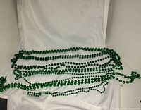 Seven green bead necklaces laid out on white backdrop