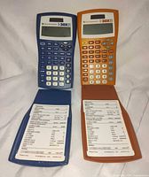 Front view of both calculators showing keypads, displays, and reference cards
