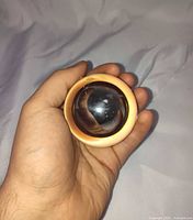 Hand holding cream acrylic ring with inner chrome sphere