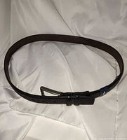 Full view of black leather belt in circular layout showing buckle and strap