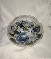 Side view of round clear glass bowl with blue and white flowers inside