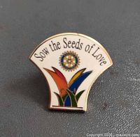 Front view of Rotary International pin showing slogan, emblem, multicolor design