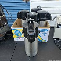 Group of air pots in cardboard box showing stainless bodies and tops