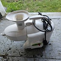 Side view of juicer main unit with power cord and feed funnel