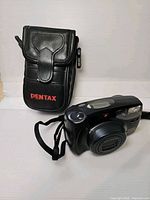 Front view of Pentax Zoom 105-R camera beside black Pentax case