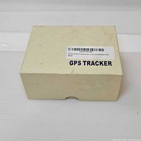 Beige product box with barcode label identifying GPS tracker