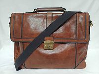 Front view of Fossil cognac leather messenger bag showing flap, push-lock clasp, and strap