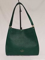 Front view of green Kate Spade shoulder bag showing logo and texture