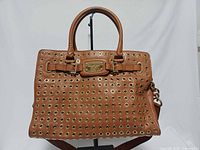 Front view showing tan leather, grommets, handles, nameplate