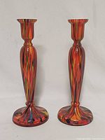 Front view of both multicolour spatter glass candlesticks standing upright