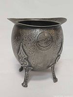 Front view showing full shape, engraved decoration, three legs