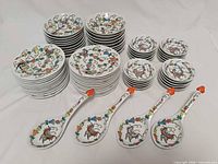 All 64 porcelain pieces grouped: four soup spoons front, stacked saucers, bowls and small dishes behind