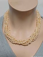 Necklace displayed on bust, full front view of pearl strands