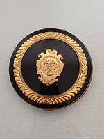 Top view showing black enamel lid, gold border, shield cartouche