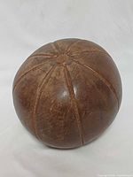 Full view of leather medicine ball showing panel stitching and wear.
