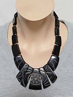 Full view of necklace on mannequin showing graduated carved panels