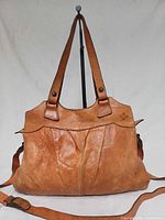 Front view of cognac leather handbag showing handles, strap and front seam details