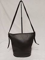 Front view of black leather bucket shoulder bag hanging