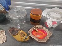 Group shot of all items including two glass jars, ceramic jar, ashtray with keyring, wooden clog