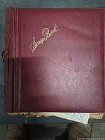 Closed scrapbook showing maroon cover labeled Scrap Book