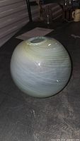 Front view of spherical pale green iridescent swirled glass vase