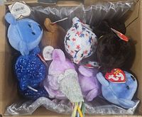 Box containing assorted Ty Beanie Baby bears showing multiple colors and attached heart tags
