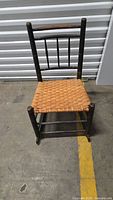 Front view of rocking chair showing woven seat and black frame