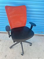 Front view showing orange mesh back, black seat, casters