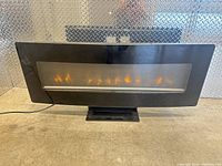 Front view of black glass electric fireplace displaying flames