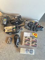 Overall view of three camcorders, digital camera, sealed tapes, lens cases and cables