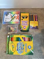 Group of art supplies including marker packs, coloured pencil packs and paper clips