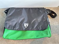 Front view of black and green messenger bag showing Lamborghini logo