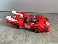 Left side view of the assembled red Lego race car with minifigure visible in cockpit