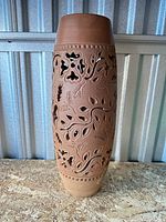 Full view of tall terracotta vase showing openwork design