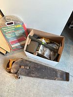 Overall view of lot: axe, toolbox, screwdriver set, lantern box, safety goggles, saw sheath, air mattress packaging