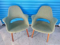 Front view of both olive organic armchairs showing design and legs
