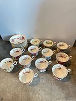 Group of 12 month-labeled teacups and stacked saucers